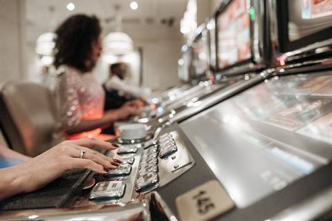 Tangan pemain menekan tombol spin pada mesin slot di kasino